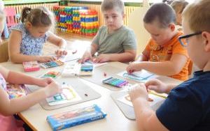 Dzieci z gr. 0A przy stoliku lepią z plasteliny