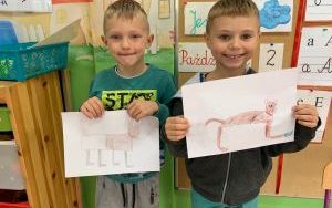 Mateusz i Natan pokazują swoje rysunki ze zwierzęcymi pupilami