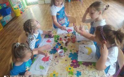 Grupa dziewczynek z gr. 0A maluje farbami obrazki z owocami