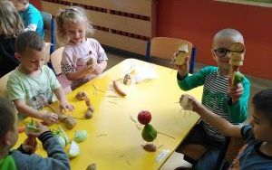 Grupa dzieci przy stoliku tworzy kukiełki z warzyw